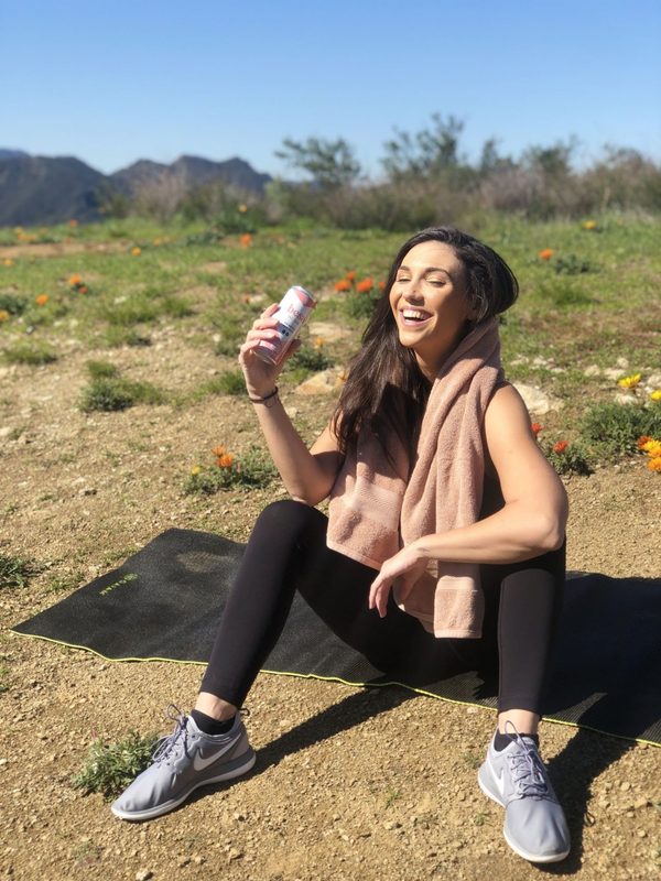 a woman in athletic clothing drinking Besa mi Vino outside
