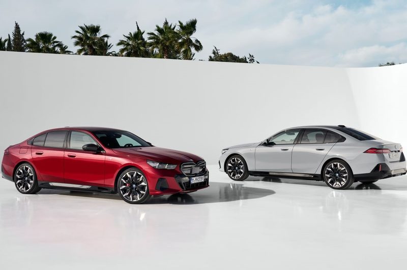 Red BMW i5 M60 xDrive and grey BMW i5 eDrive40 parked in a white studio background.