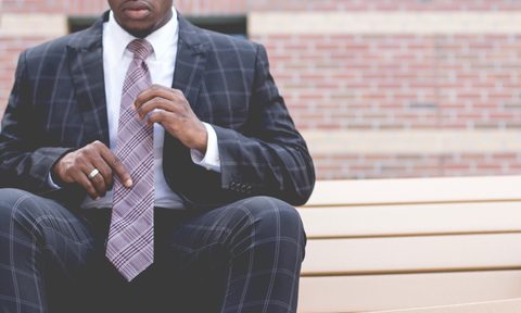 Man sitting on a step adjusting his tie