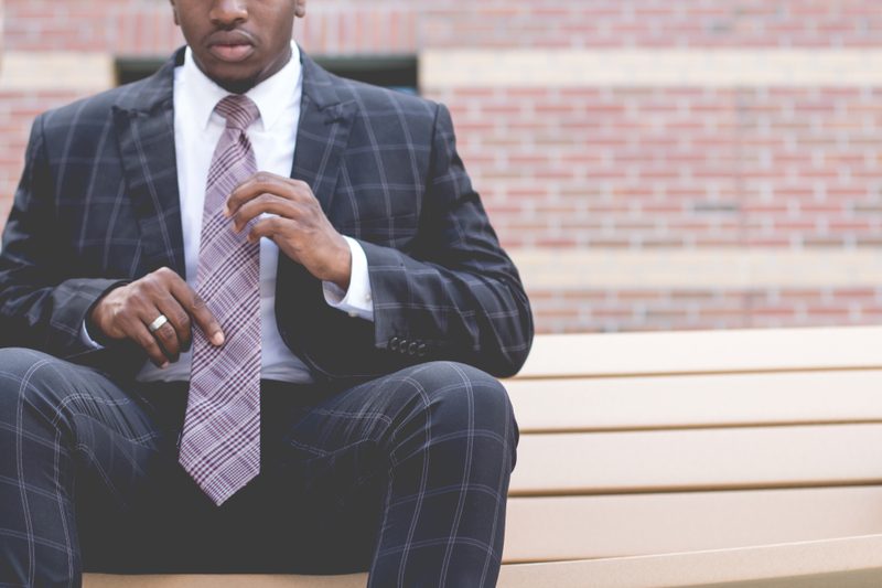 Man sitting on a step adjusting his tie