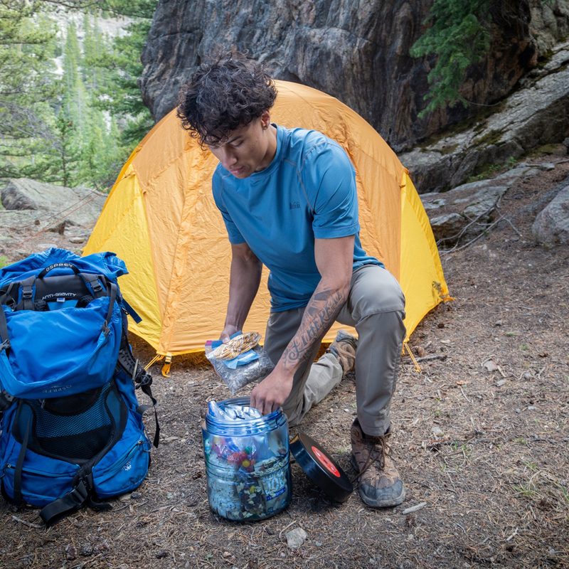 Young hiker stashing food in a BearVault BV475 Trek Bear Canister.