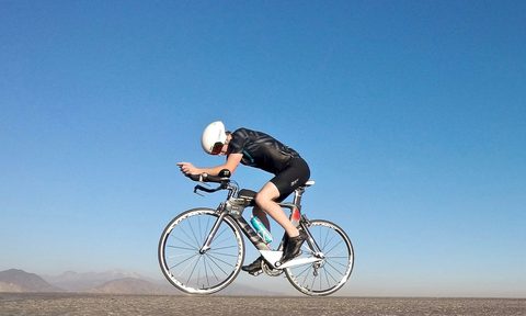 Cyclist balancing on a bike in a barren landscape.