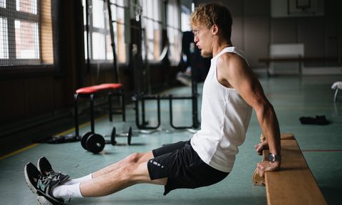 A man doing a tricep bench dip white shirt