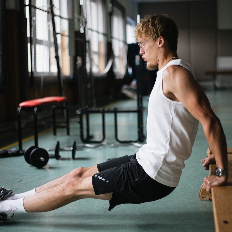A man doing a tricep bench dip white shirt