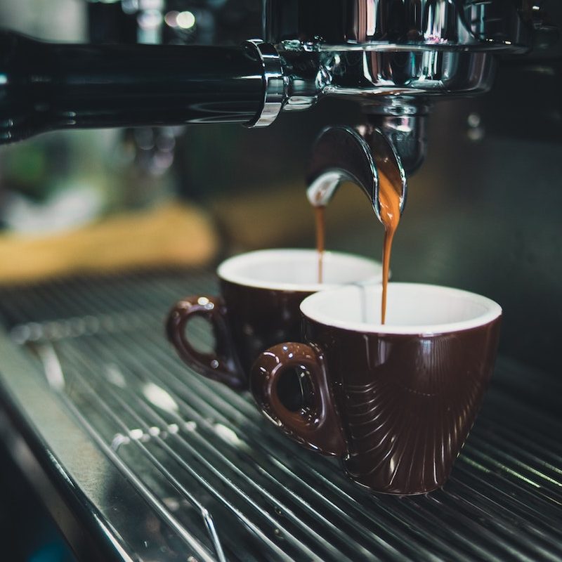 Two cups of coffee being made at a shop