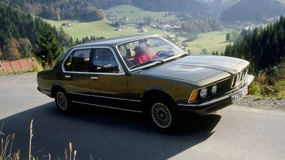 An old BMW 7 Series car being driven up a hill.
