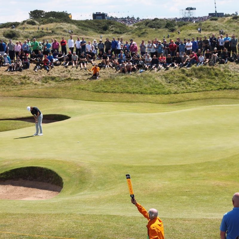 A crowd watching a golfer take a shot.