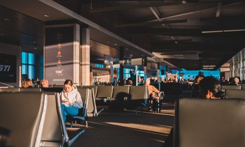 A view of a crowded airport with people sitting in the seats.
