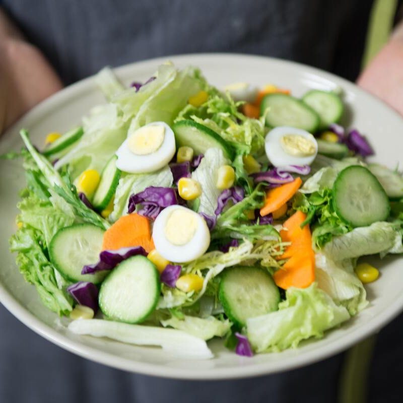 Person holding a bowl of salad