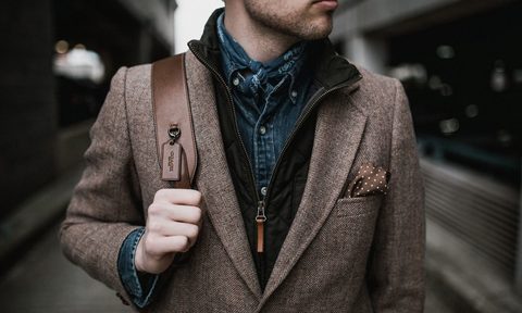 A man dressed stylishly holding onto a shoulder bag