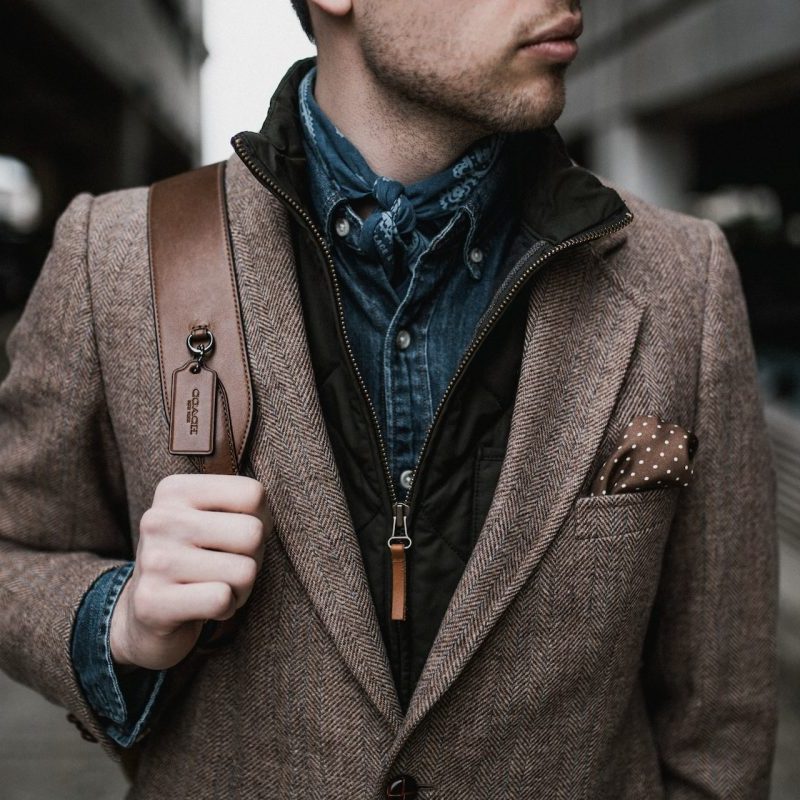 A man dressed stylishly holding onto a shoulder bag