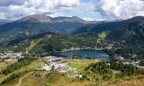 A ski resort in the summer with a lake and resort buildings.