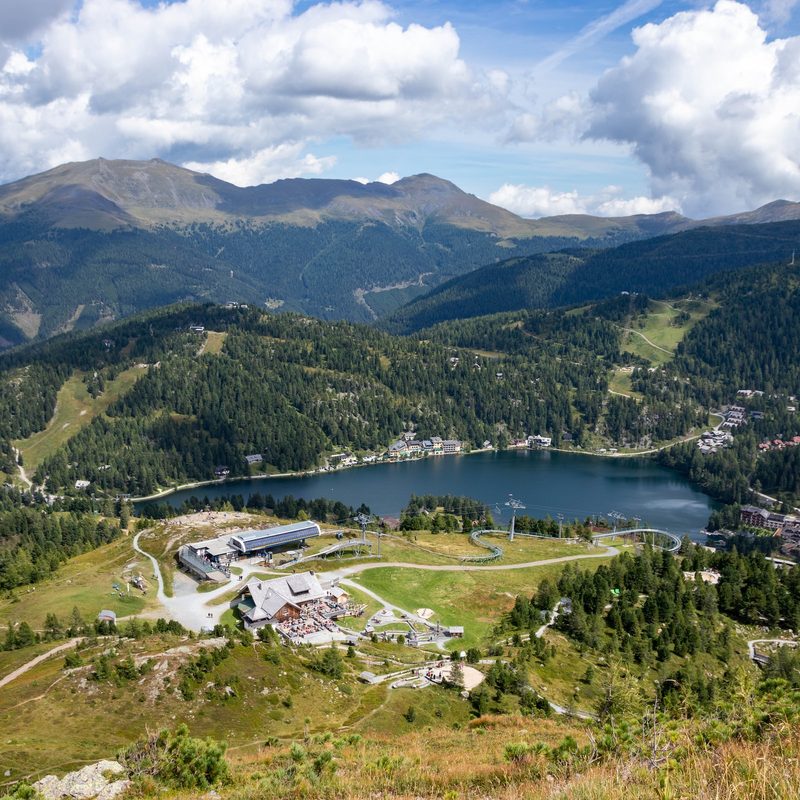 A ski resort in the summer with a lake and resort buildings.