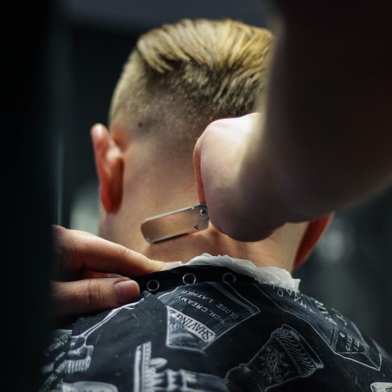 man putting finishing touches on another man's haircut