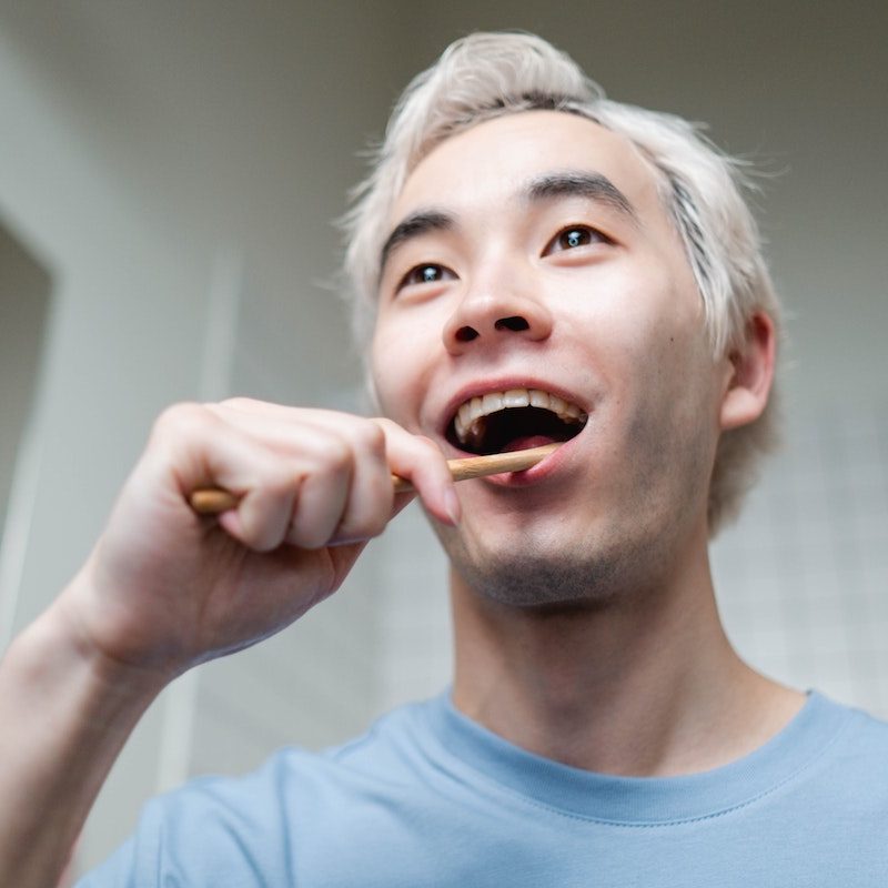 A man in a blue sweatshirt brushing his teeth