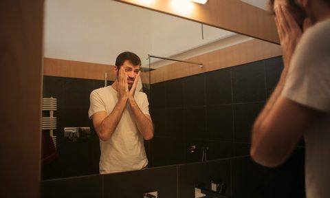 a man looking upset in the mirror