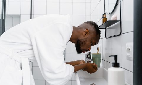 a man in a white robe washing face
