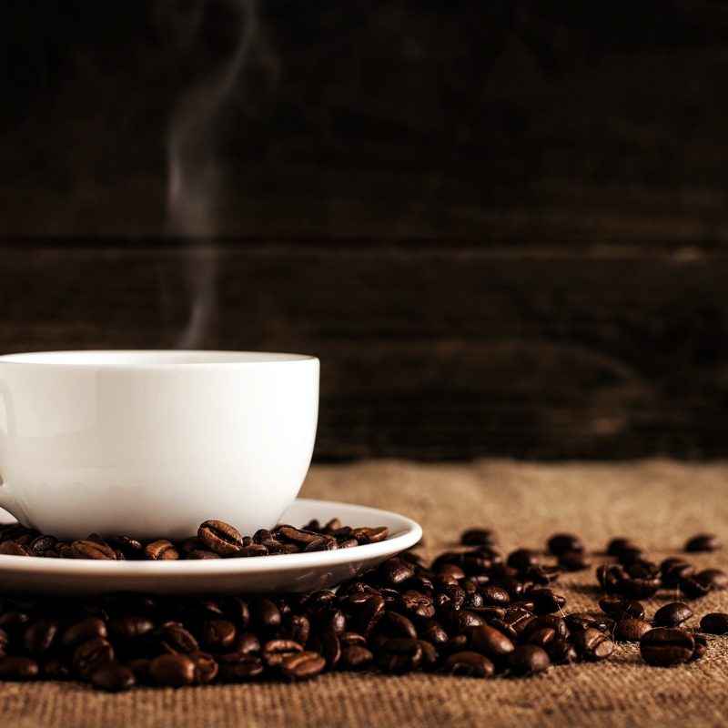 Cup of coffee with beans on table