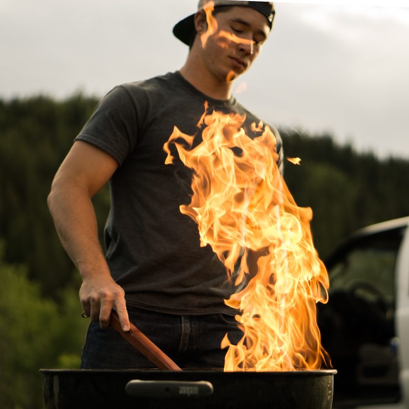 Man grilling over large flame