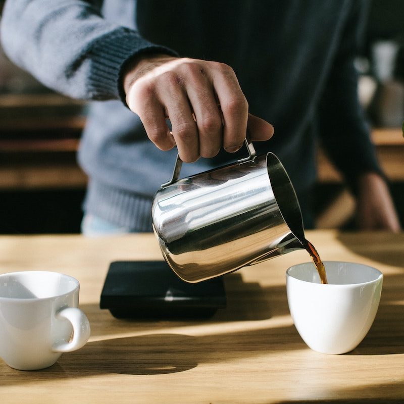 Man in blue sweater making cup of coffee