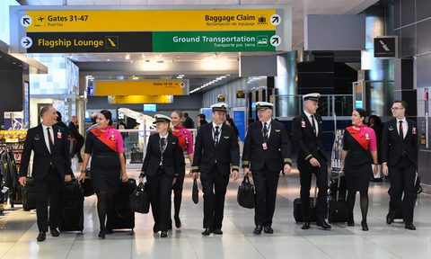 A Qantas flight crew walking through the airport.