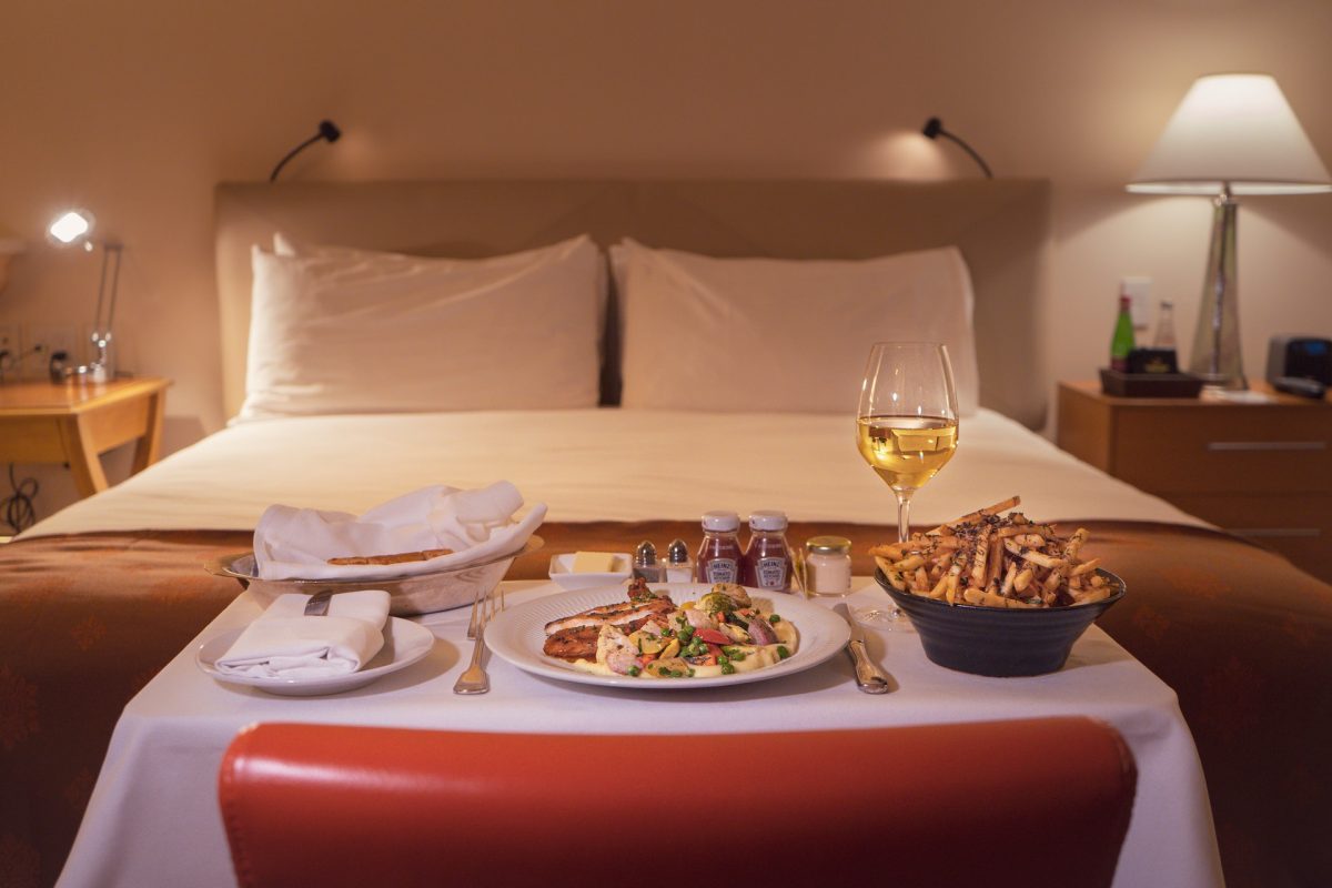 A hotel room bed with room service tray at the foot.