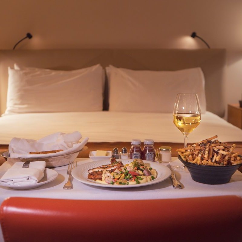 A hotel room bed with room service tray at the foot.