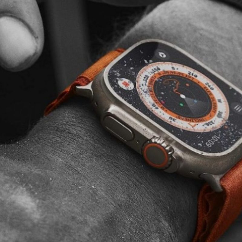 The Apple Watch Ultra covered in just a touch of sand on the arm of a man doing tough work.