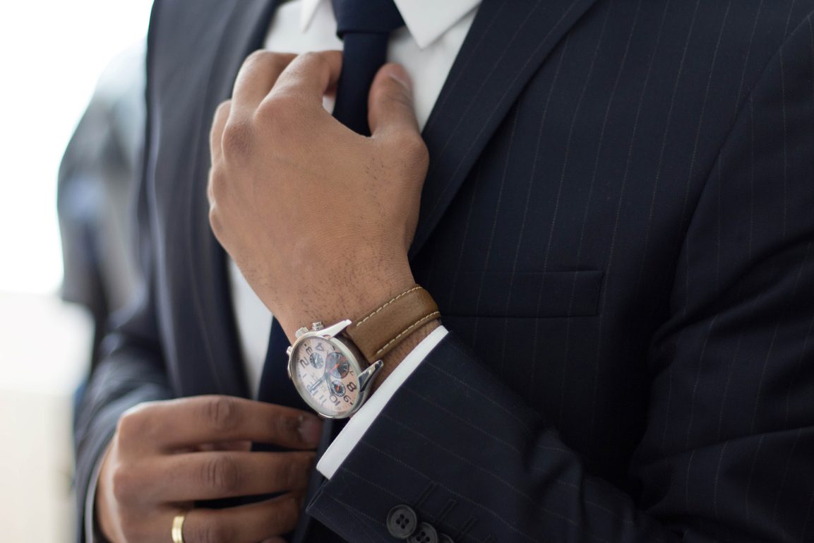 Man adjusting his tie wearing a watch