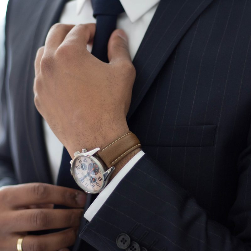 Man adjusting his tie wearing a watch