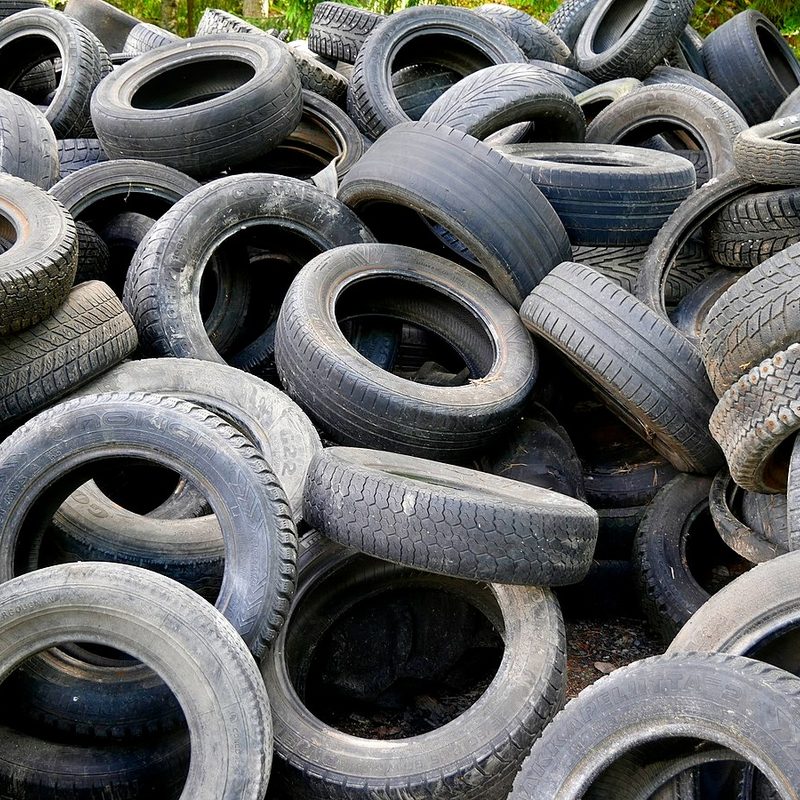 A heap of used car tires in different stages of use.