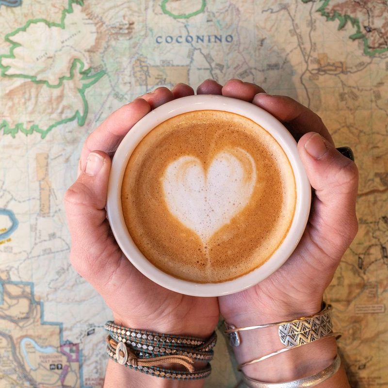 A person holds a cup of cappuccino at Late for the Train.
