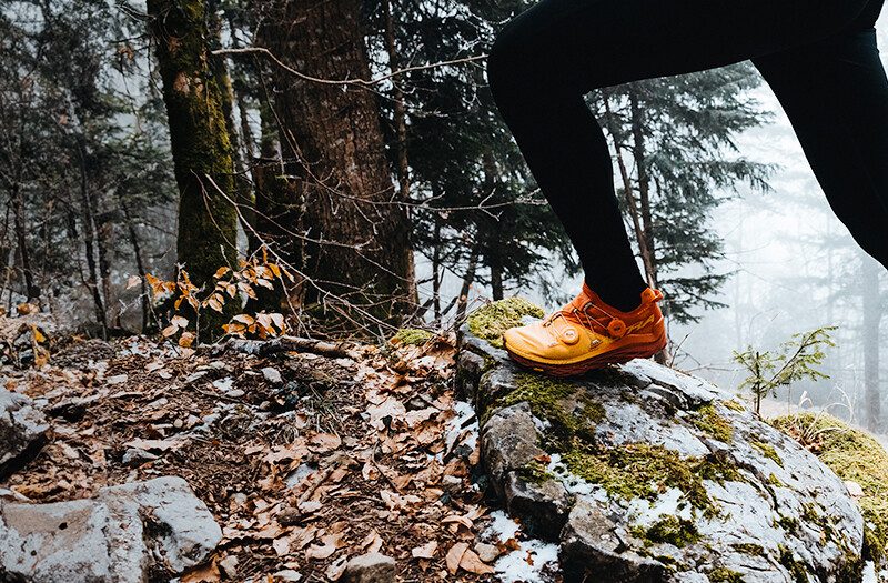 A close up of a trail runner's legs wearing bright orange Altra shoes.