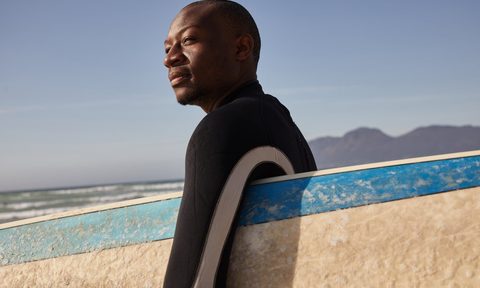 Bald man holding surfboard in the sun