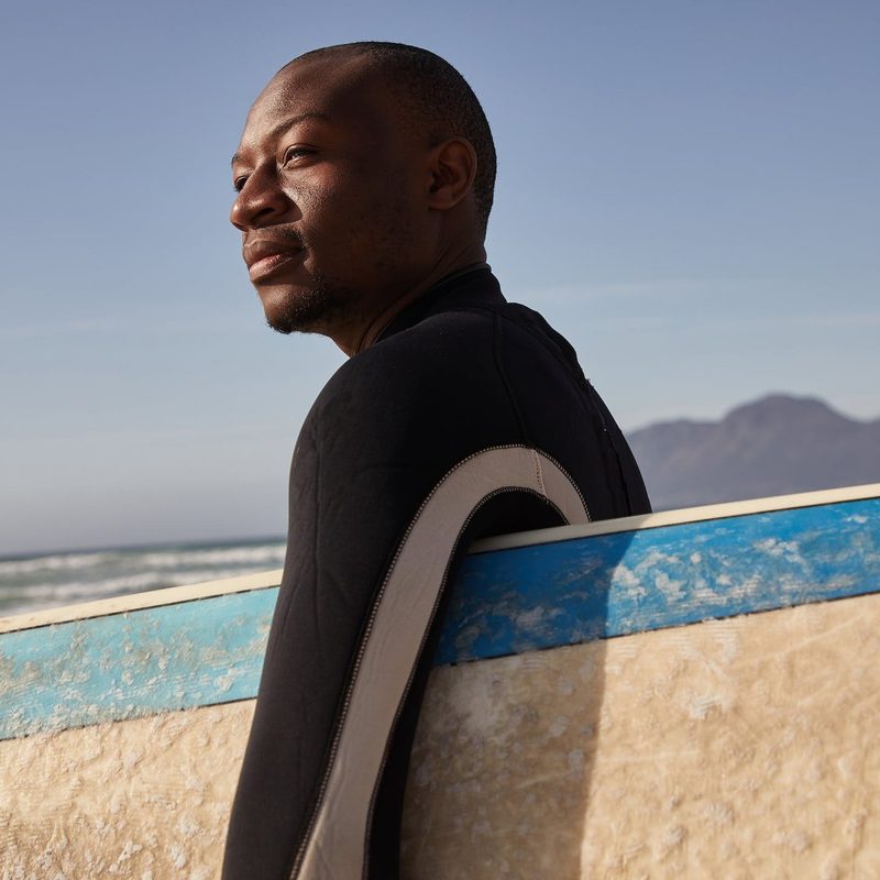 Bald man holding surfboard in the sun