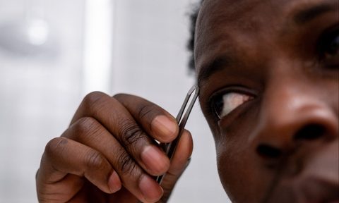 Man plucking eyebrows with tweezers