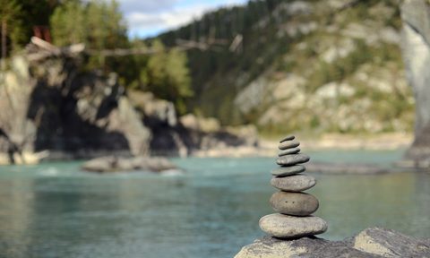 A rock cairn near mountains and water.