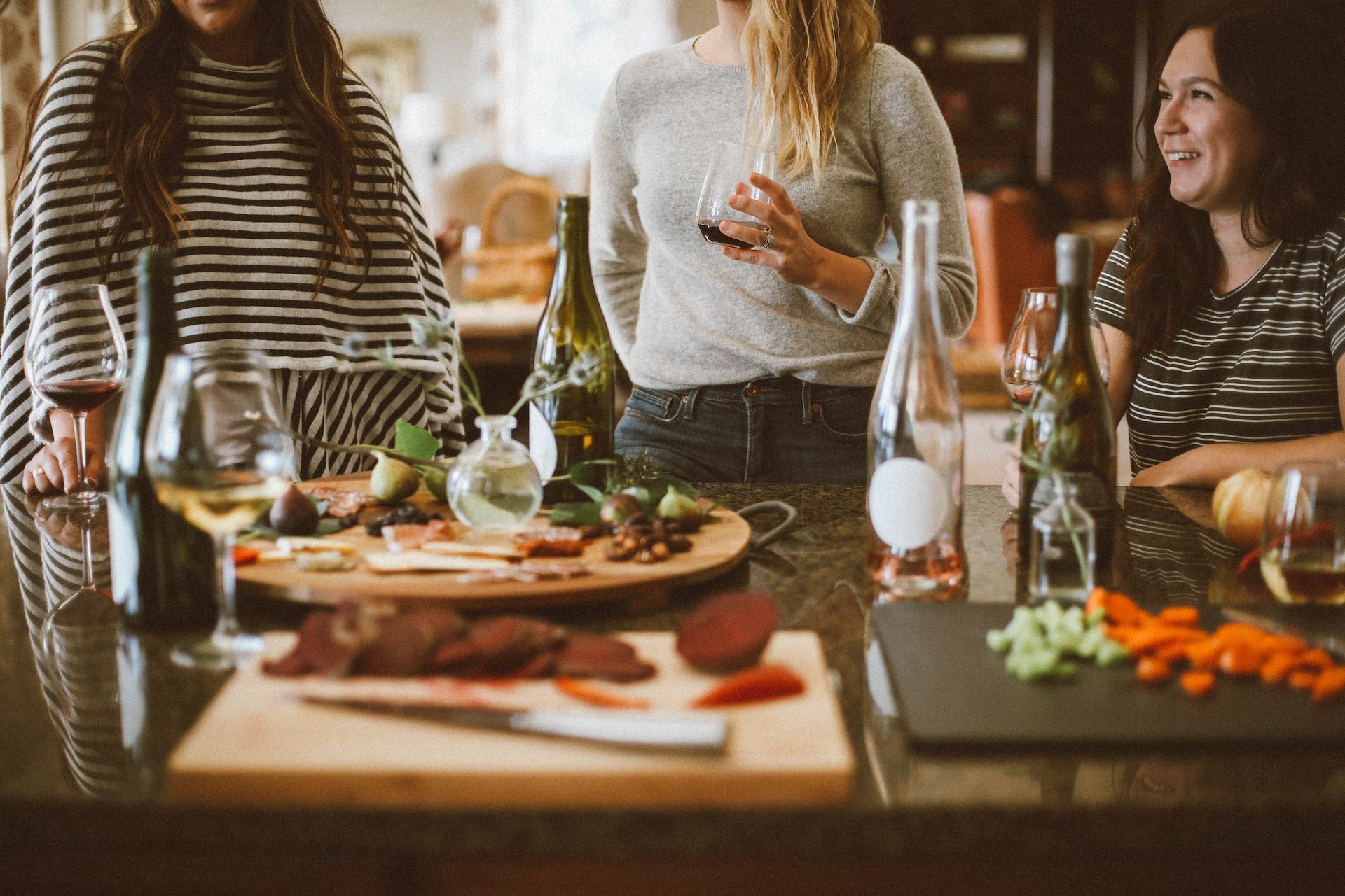 People in kitchen with food and wine