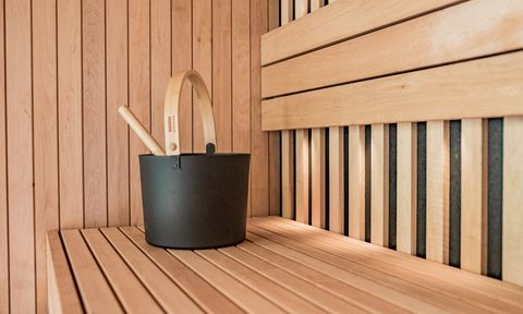Black sauna bucket on top of a sauna bench.