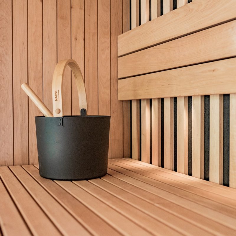 Black sauna bucket on top of a sauna bench.