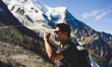 Man drinking from water bottle on mountain
