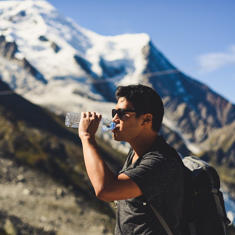 Man drinking from water bottle on mountain
