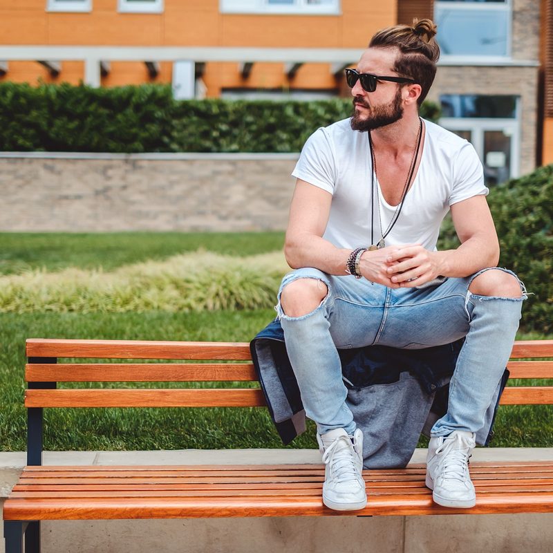 Man sitting on bench with ripped jeans