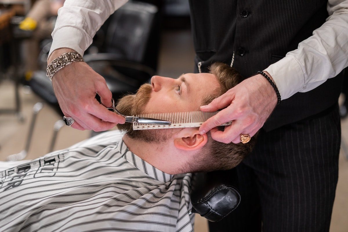 a man getting his beard trimmed at the barber