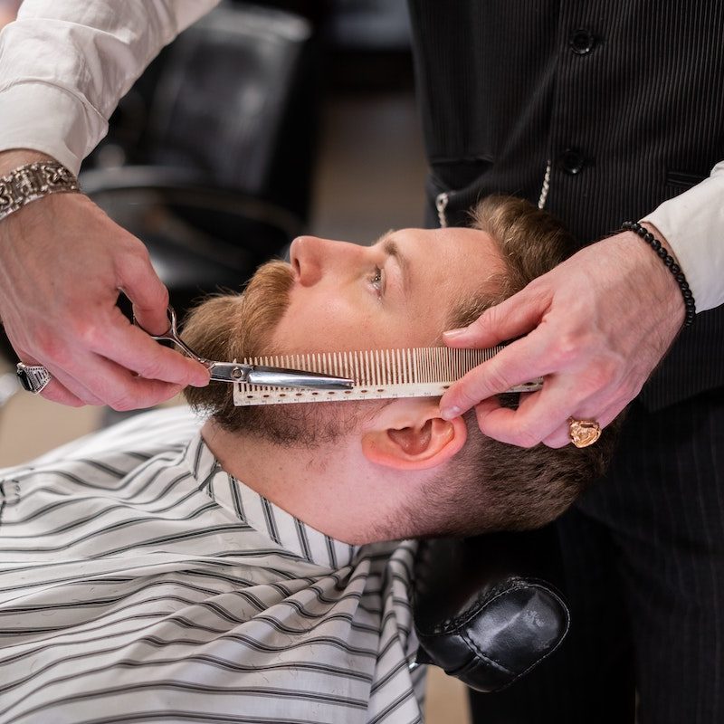 A man getting his beard trimmed at the barber