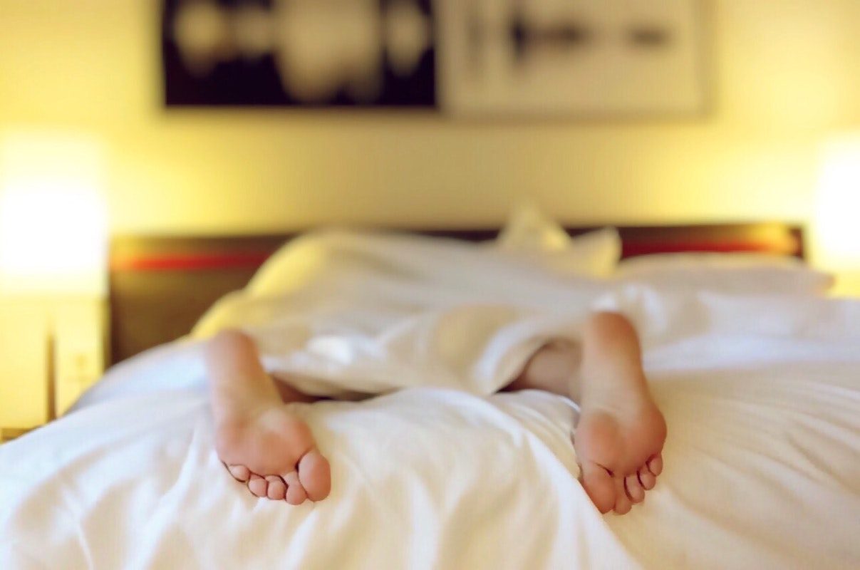 man sleeping in bed with white sheets