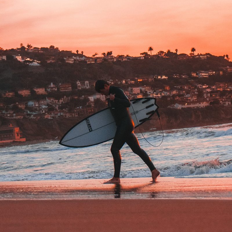 Surfer in a wetsuit walking away from the water on Los Angeles' Torrance Beach