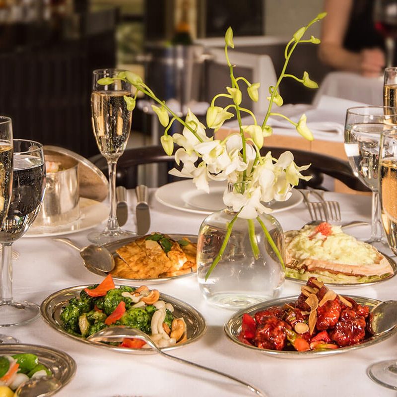 A dining room table with plates full of food at Mr. Chow at Caesars Palace Las Vegas.