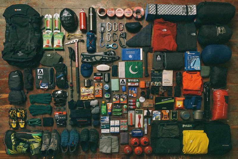 Flat lay of hiking and camping gear spread out on a hardwood floor.