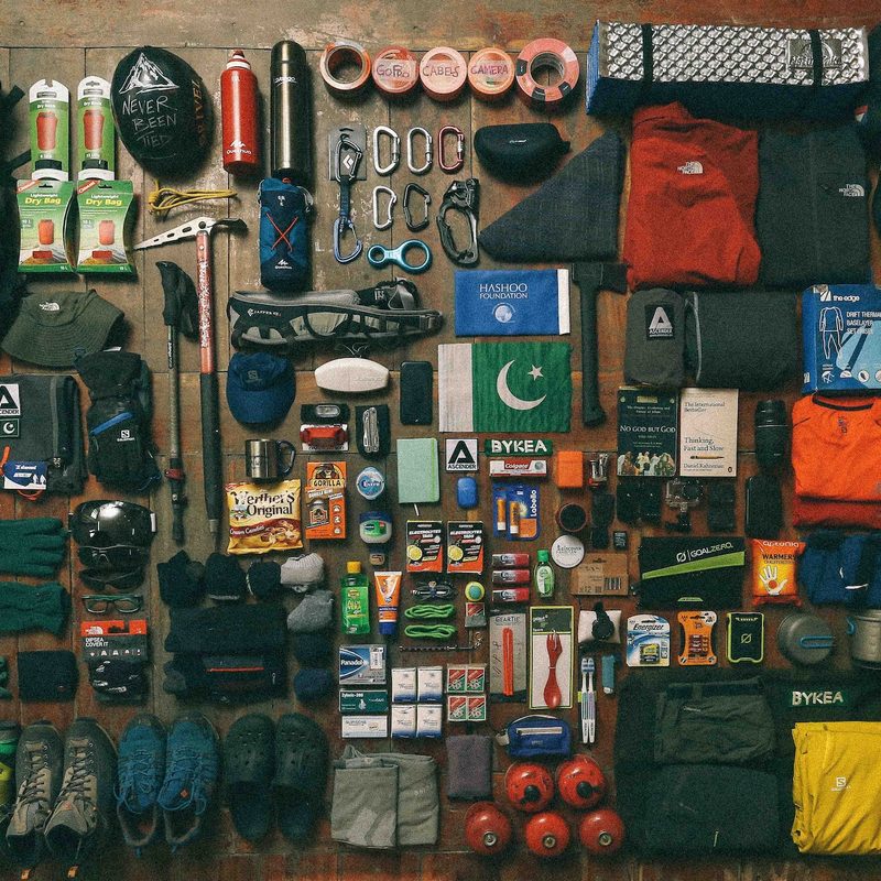 Flat lay of hiking and camping gear spread out on a hardwood floor.